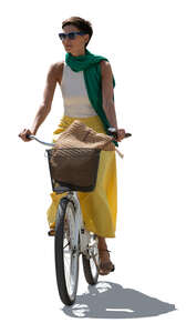 backlit woman in a colorful outfit riding a bike