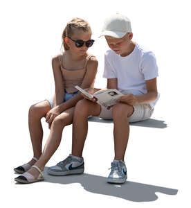 two children sitting and looking at a book