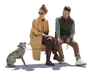 cut out backlit man and woman sitting and looking at their dog