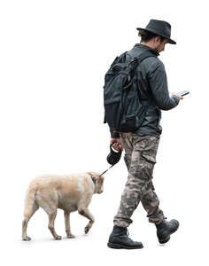 man walking with a dog and checking his phone