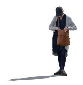 backlit woman standing and looking for something from her purse