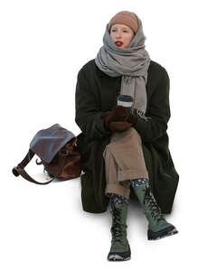 cut out young woman in winter sitting and drinking coffee