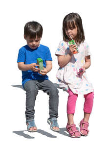 two kids with juice boxes sitting and drinking