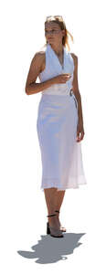 backlit elegant woman in a white dress standing and drinking wine