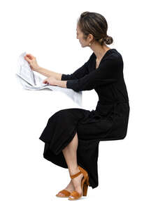 asian woman in a black dress sitting at a table and reading a newspaper