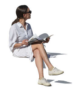 woman in a summer dress sitting and reading a magazine