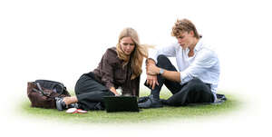 man and woman sitting on the grass and watching laptop together