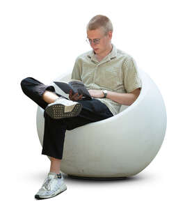 young man sitting in a modern armchair and reading a book