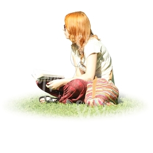 red-haired woman sitting on the grass and reading a book