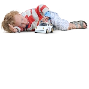 little boy lying and playing with a toy car