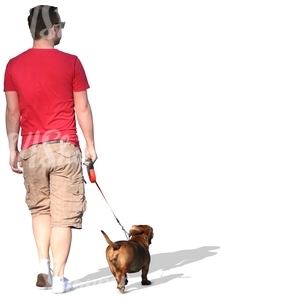 man in a red T-shirt walking a dog