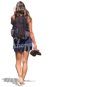 woman in a summer dress walking barefoot and carrying her sandals