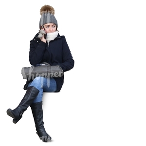woman in a winter coat sitting and talking on the phone