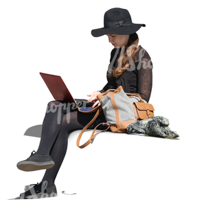 woman with a large hat sitting and working with a laptop.