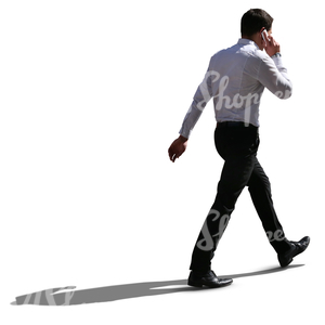 backlit businessman walking and talking on the phone