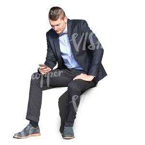 young man wearing a suit sitting and browsing his phone