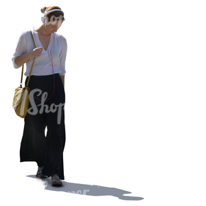 backlit woman with headphones walking and listening to music