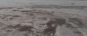 worn asphalt field with wet spots