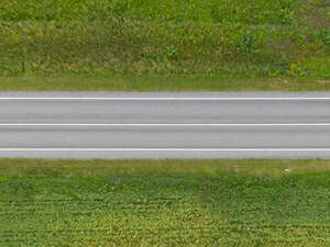 aerial view of an asphalt road between grasslands