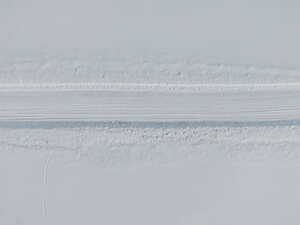 snow covered road between snow fields seen from above