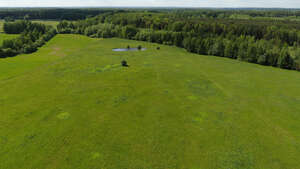 aerial view  of a countryside with green meadows and forests and a lake