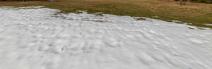 grass field with large patch of snow