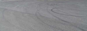 light grey aspahlt field with tyre tracks