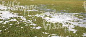 grass field partially covered with snow and ice