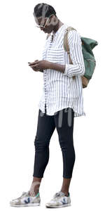 black woman in a striped white shirt standing and looking at her phone