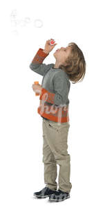 young boy standing and blowing bubbles