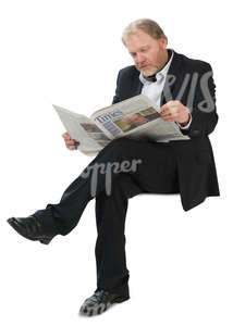 man in a suit sitting and reading a newspaper