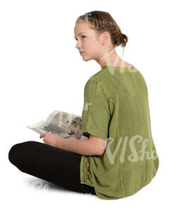 teenage girl sitting on a floor and reading a magazine