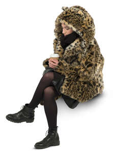 woman in a faux fur coat sitting and drinking coffee