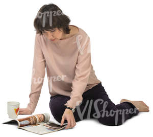 woman sitting on the floor and looking at a magazine