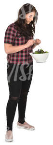 young woman standing in a kitchen and mixing salad