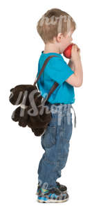 little boy standing and eating an apple