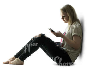 backlit woman sitting by the window and looking at her phone 