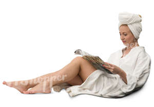 woman in a white bathrobe sitting and reading a magazine