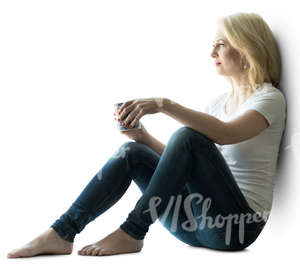 backlit woman sitting by the window and drinking coffee