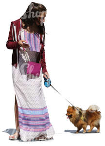 woman in a long summer dress walking a dog