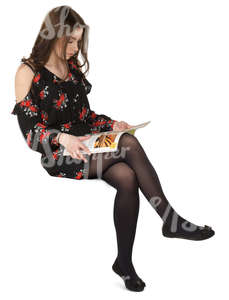 woman in a dress sitting and reading a magazine