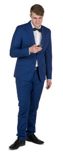 young man in a blue suit standing and texting