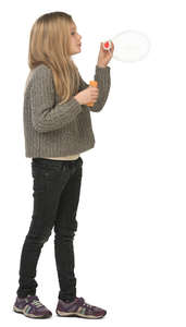 young girl standing and blowing soap bubbles