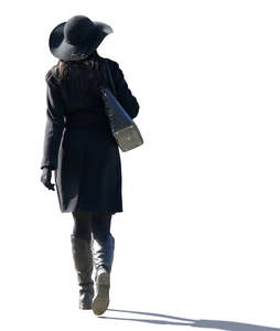 backlit woman with a black hat walking