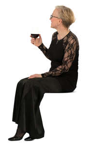 woman in a formal black dress sitting and drinking wine