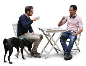 two men and a dog sitting in a cafe