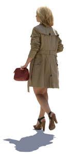 backlit woman in a trenchcoat walking