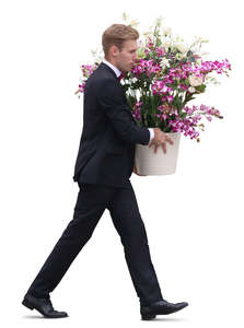 man in a black suit carrying a pot of flowers