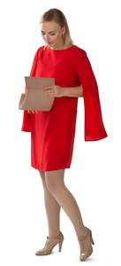 woman in a red dress standing and searching for smth in her purse