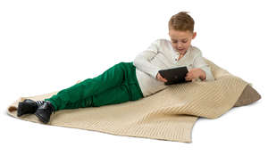 boy lying on a cushion and looking at a tablet